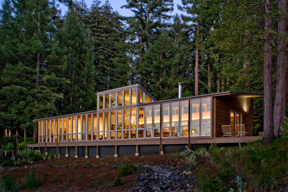 Example of a mountain style two-story glass exterior home design in San Francisco with a shed roof