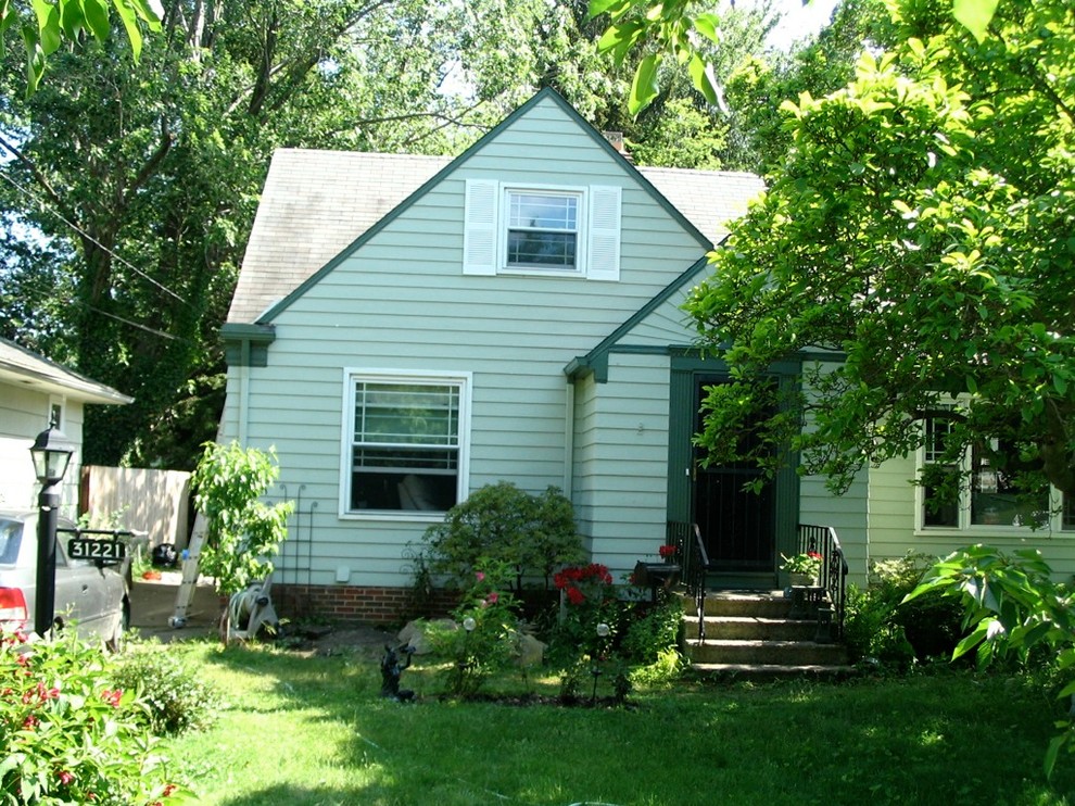 На фото: маленький, одноэтажный, зеленый дом в классическом стиле с комбинированной облицовкой для на участке и в саду