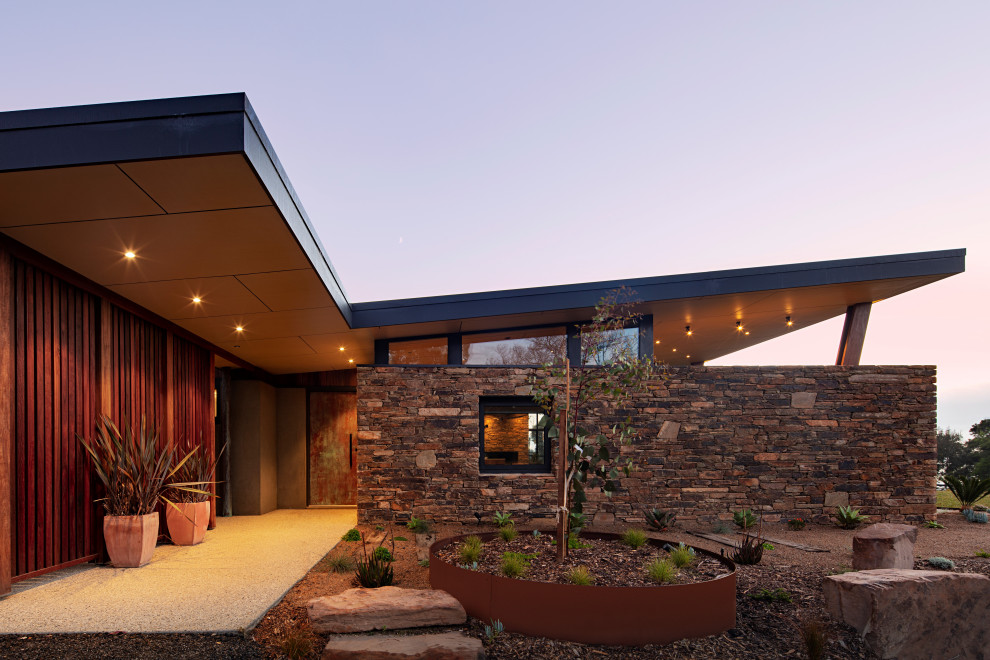 Стильный дизайн: одноэтажный частный загородный дом среднего размера в стиле ретро с облицовкой из камня и металлической крышей - последний тренд