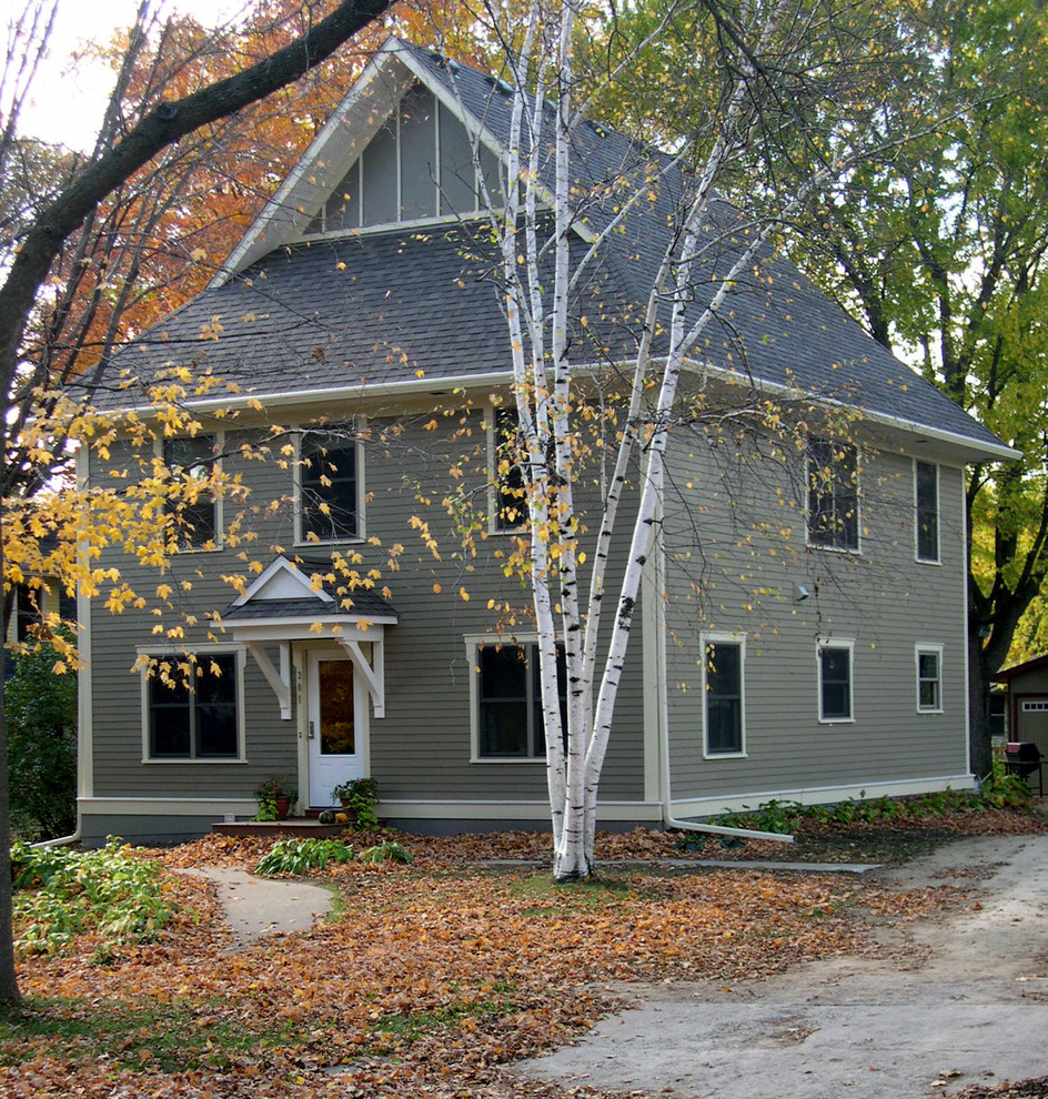 Réalisation d'une façade de maison grise tradition en panneau de béton fibré de taille moyenne et à un étage avec un toit à quatre pans.