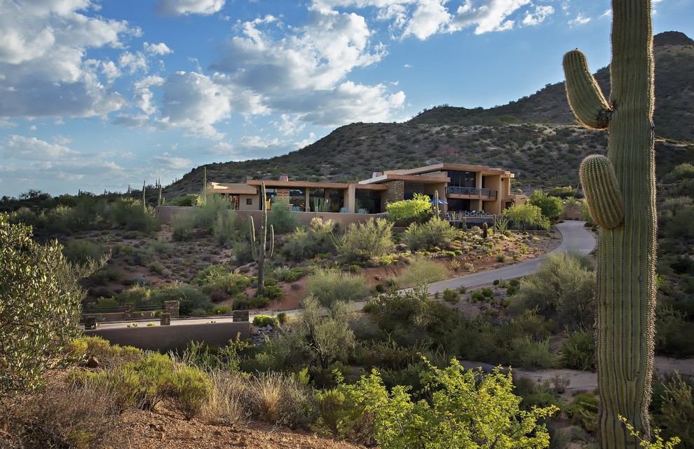 Example of a large trendy beige two-story stucco exterior home design in Phoenix with a shed roof