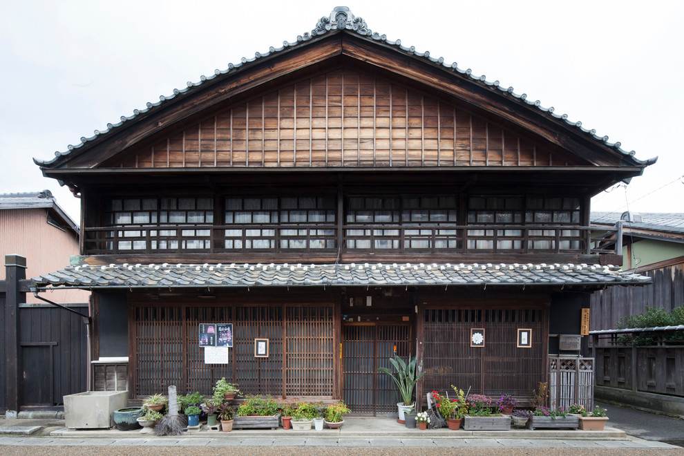 Идея дизайна: трехэтажный, коричневый дом в японском стиле в восточном стиле с комбинированной облицовкой и двускатной крышей