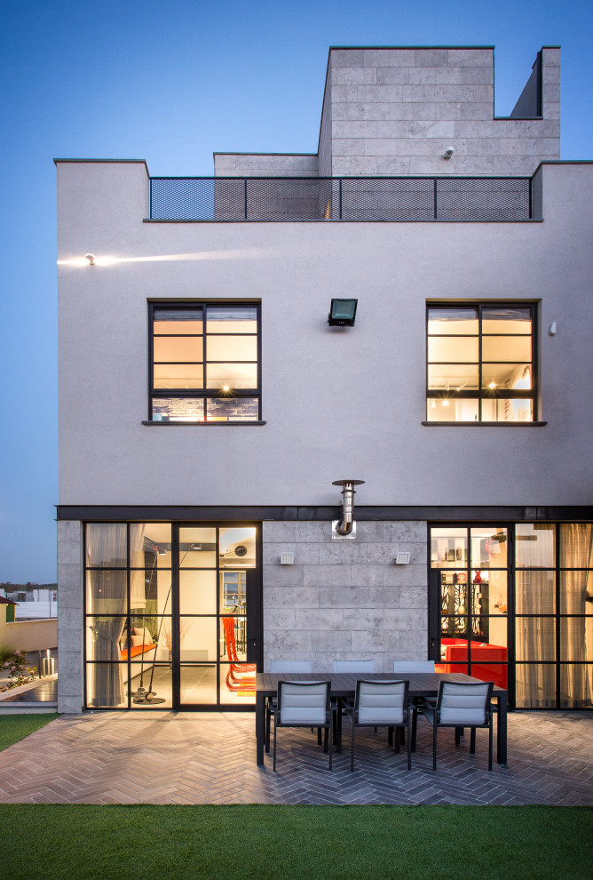 Mittelgroßes, Dreistöckiges Industrial Einfamilienhaus mit Steinfassade, grauer Fassadenfarbe, Flachdach und Ziegeldach in Tel Aviv