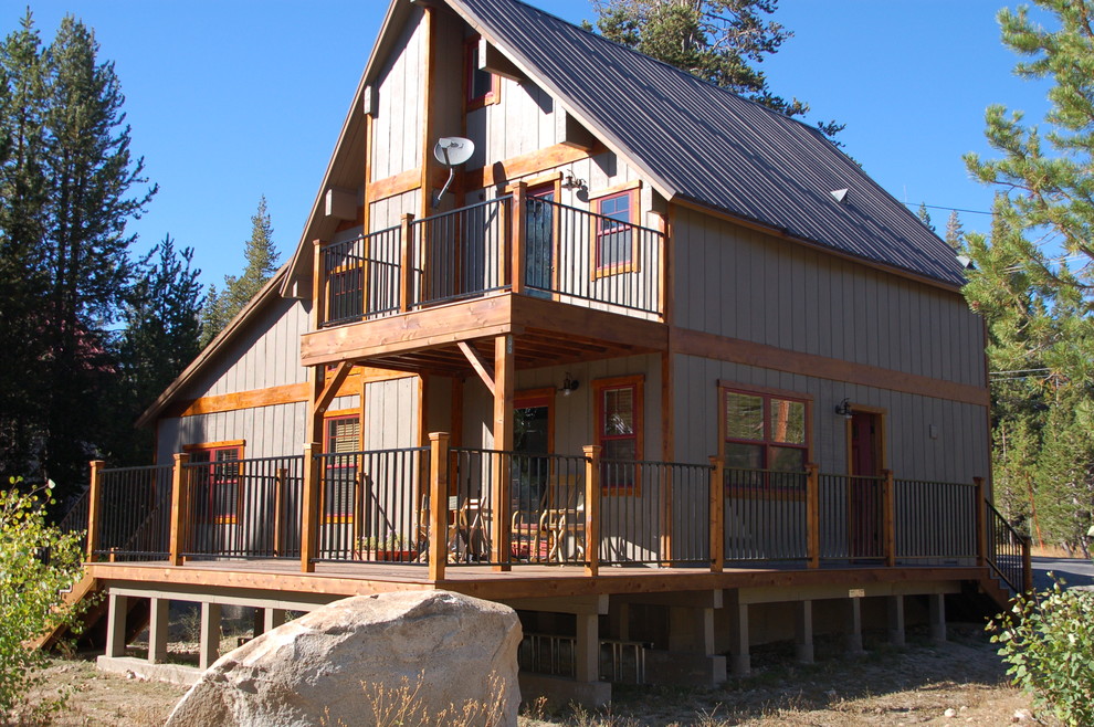 Inspiration pour une façade de maison grise chalet en bois de taille moyenne et à un étage avec un toit à deux pans et un toit en métal.