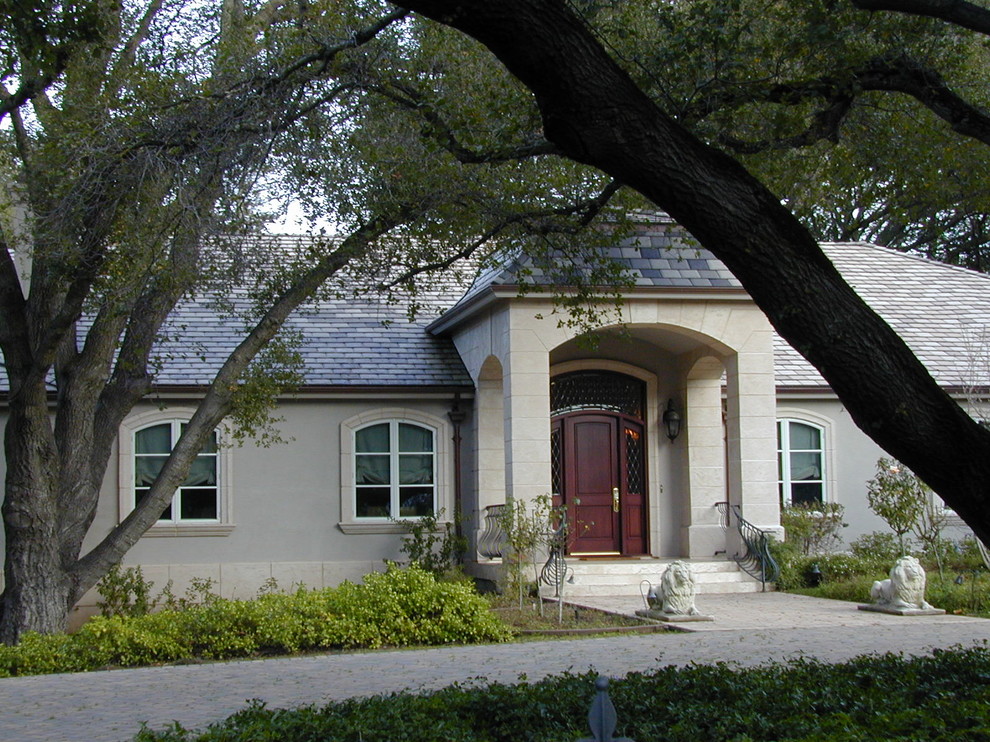 Cette photo montre une très grande façade de maison grise rétro en stuc de plain-pied avec un toit à quatre pans.