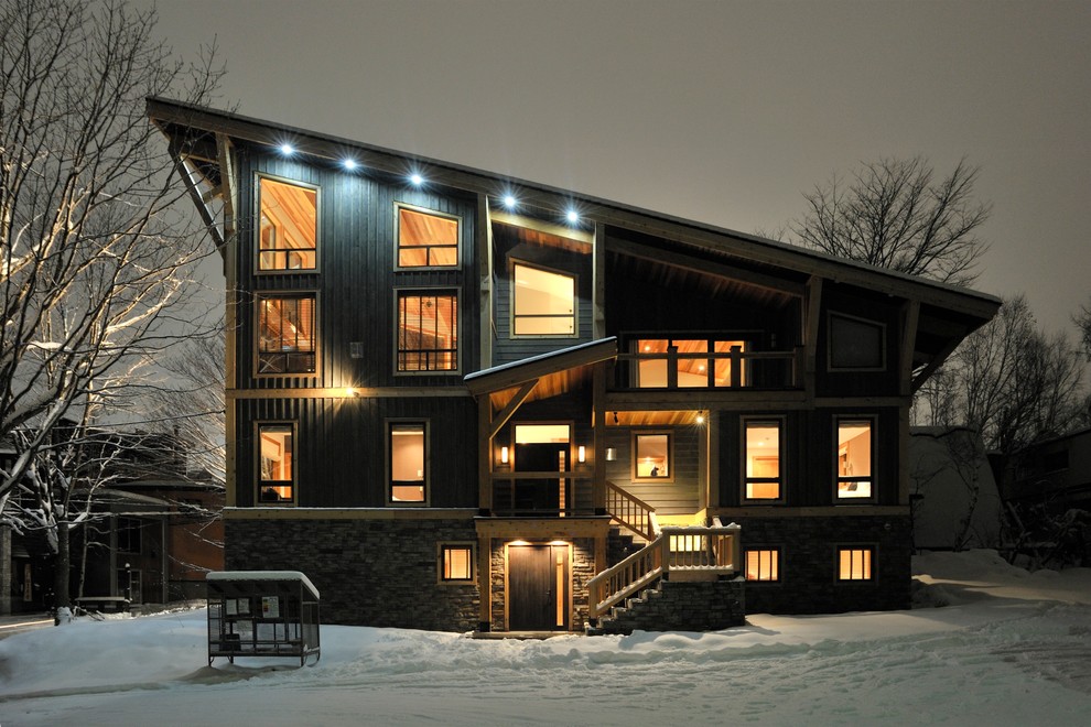 На фото: трехэтажный, деревянный, черный дом в современном стиле с односкатной крышей с
