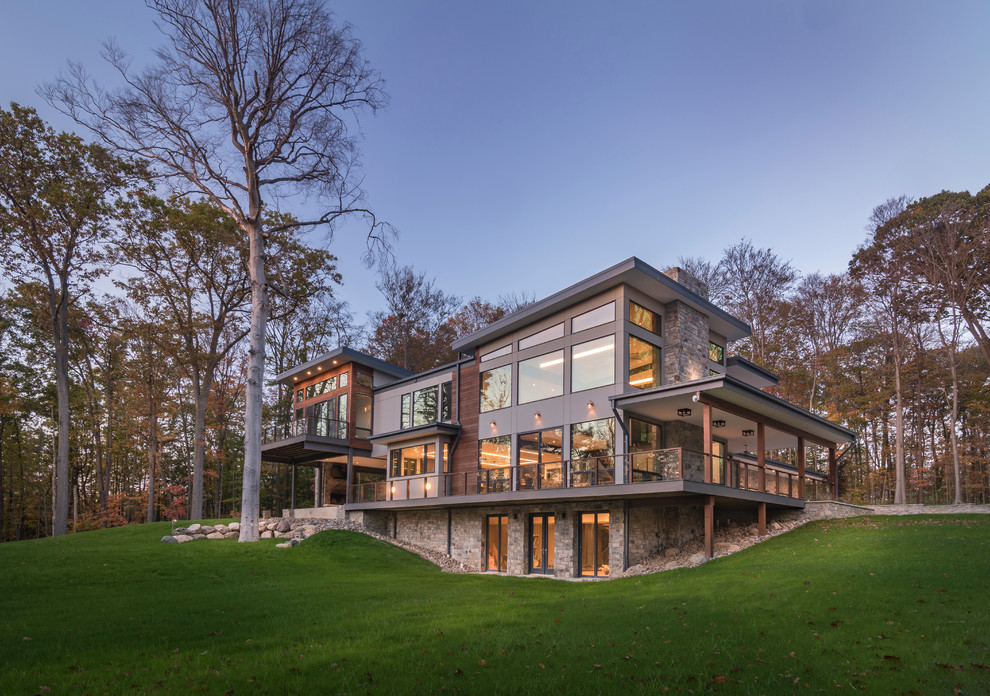 Large minimalist gray two-story stone exterior home photo in Cleveland with a mixed material roof