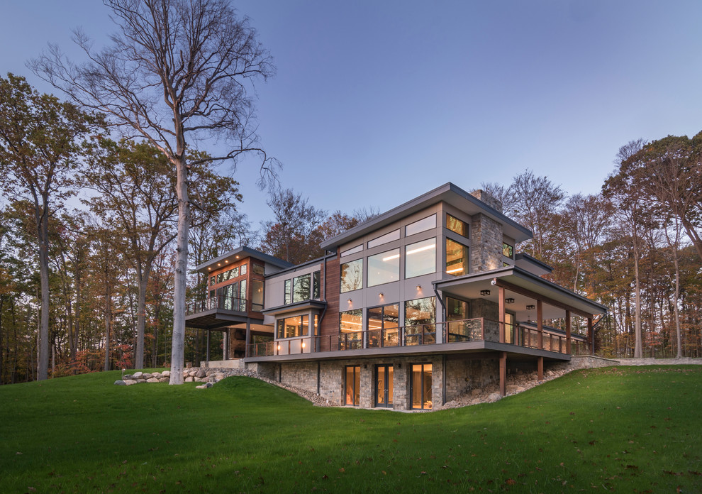 Large minimalist gray two-story stone exterior home photo in Cleveland with a mixed material roof