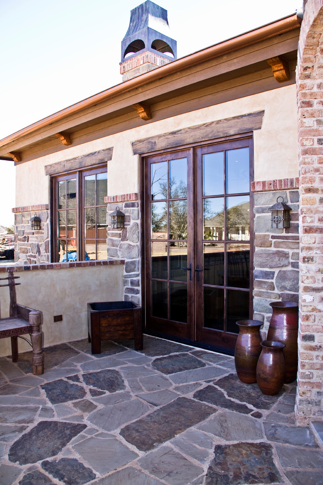 This is an example of a mediterranean bungalow house exterior in Austin with stone cladding.