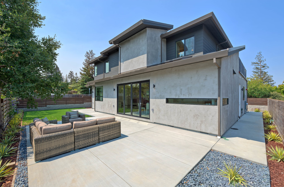 Cette image montre une façade de maison grise design en panneau de béton fibré de taille moyenne et à un étage avec un toit à deux pans.