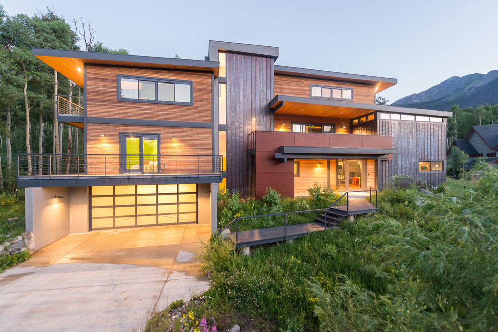 Ejemplo de fachada de casa marrón minimalista de tamaño medio de tres plantas con revestimiento de madera y tejado plano