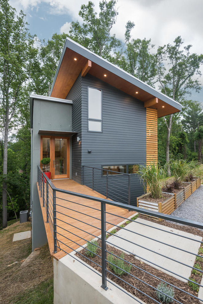 На фото: трехэтажный, серый частный загородный дом в стиле модернизм с облицовкой из ЦСП, односкатной крышей и металлической крышей