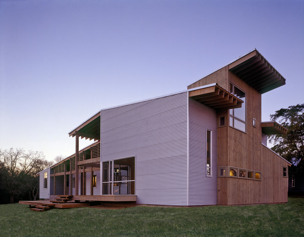 На фото: маленький, двухэтажный, серый дом в стиле модернизм с комбинированной облицовкой и двускатной крышей для на участке и в саду