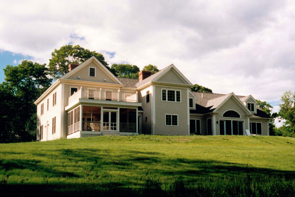 Esempio della villa grande beige classica a due piani con rivestimento in legno, tetto a capanna e copertura a scandole