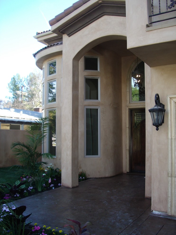 Ejemplo de fachada de casa beige mediterránea de tamaño medio de dos plantas con revestimiento de estuco, tejado a dos aguas y tejado de teja de madera