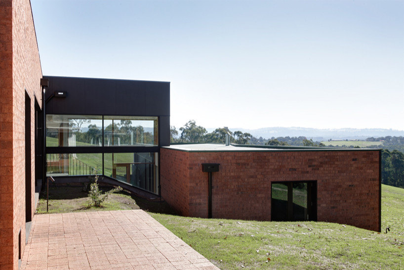 Foto della villa ampia nera moderna a piani sfalsati con rivestimento in mattoni, tetto piano e copertura mista