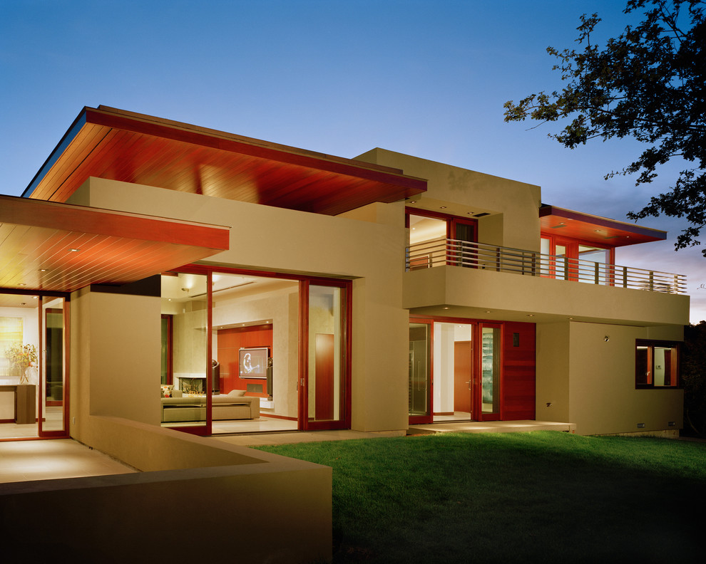 На фото: большой, двухэтажный, бежевый дом в стиле модернизм с комбинированной облицовкой и плоской крышей