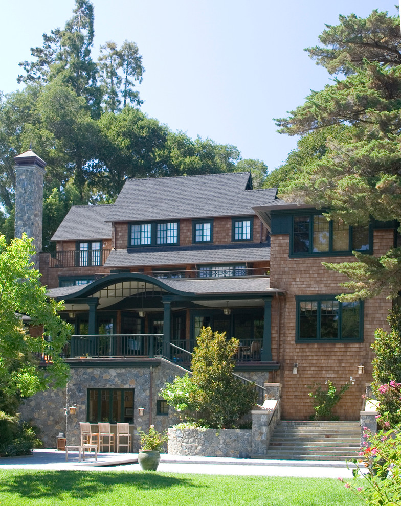 Esempio della facciata di una casa marrone american style a tre piani con rivestimento in legno e tetto a capanna