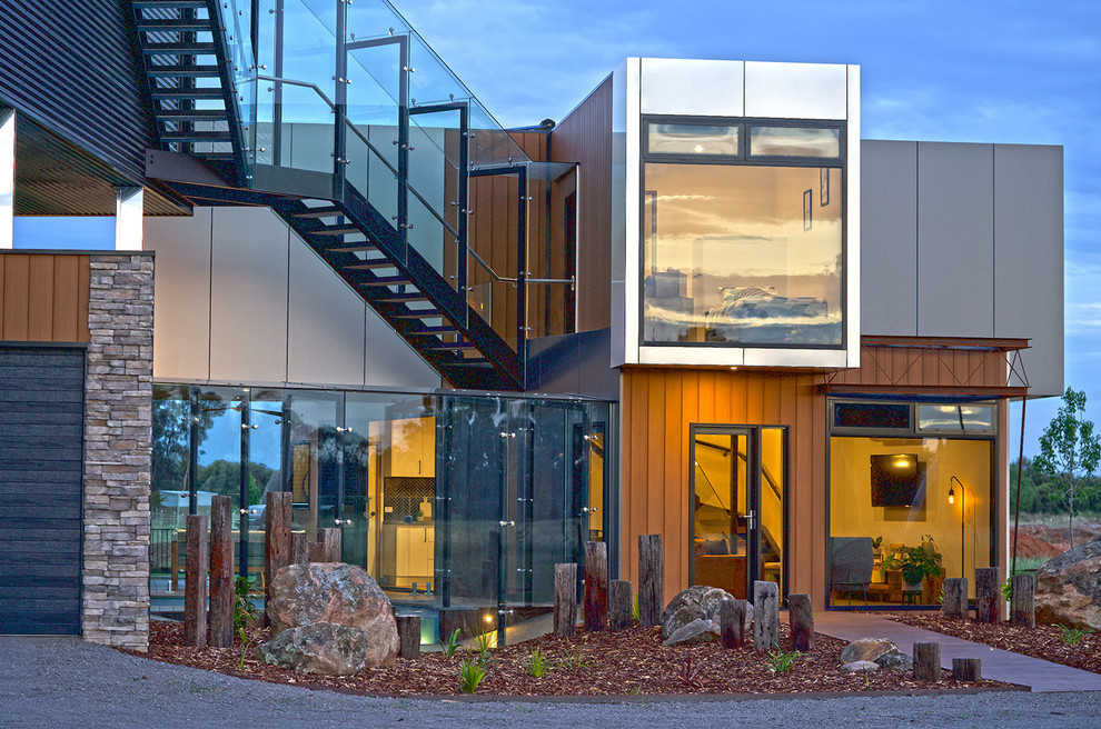 Aménagement d'une très grande façade de maison container grise contemporaine en bois à un étage avec un toit plat et un toit en métal.