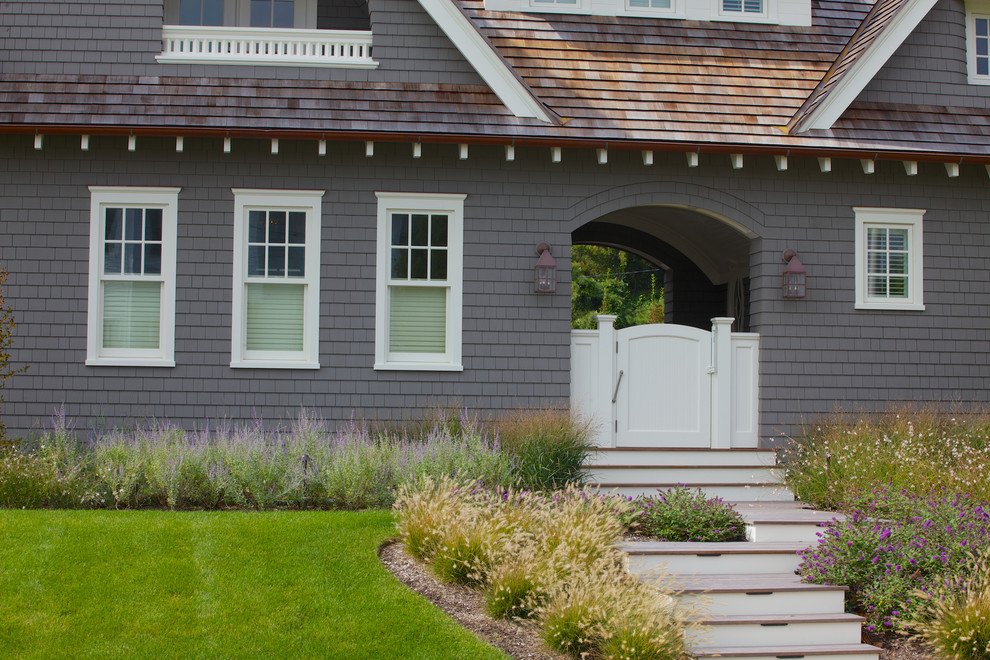 Diseño de fachada de casa gris costera grande de dos plantas con revestimiento de madera, tejado a dos aguas y tejado de teja de madera