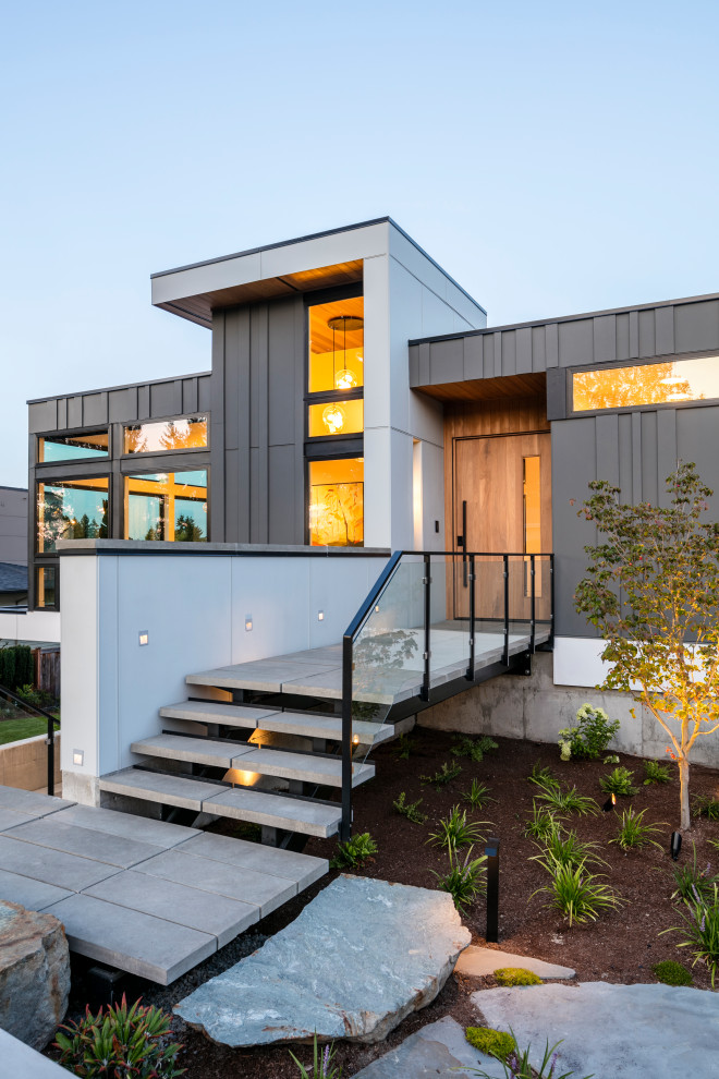 Cette photo montre une grande façade de maison grise moderne à un étage avec un revêtement mixte et un toit plat.