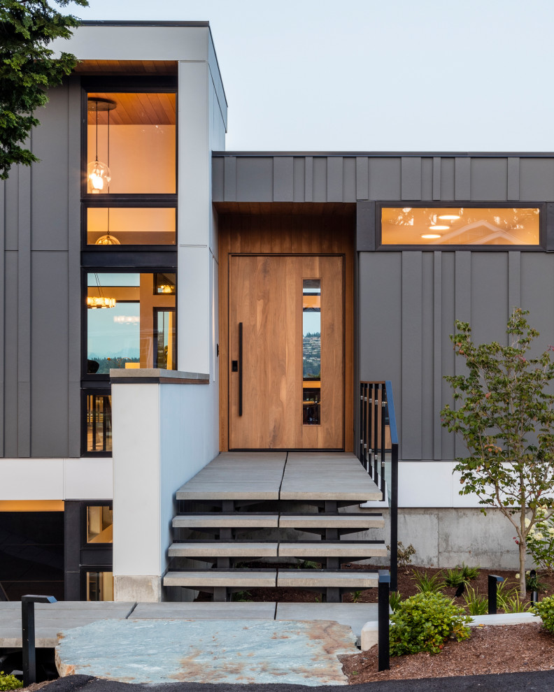 На фото: большой, двухэтажный, серый частный загородный дом в стиле модернизм с комбинированной облицовкой и плоской крышей с