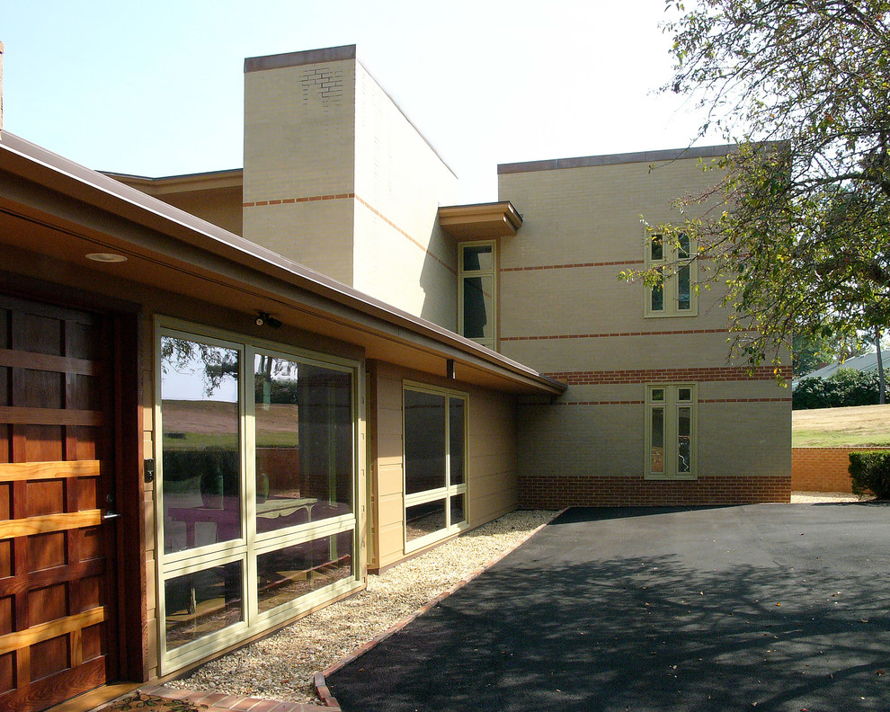 Idée de décoration pour une façade de maison beige design en brique de taille moyenne et à un étage avec un toit plat et un toit en shingle.
