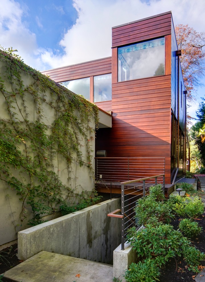 Inspiration pour une façade de maison design en bois de taille moyenne et à niveaux décalés avec un toit plat.
