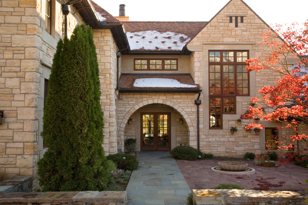 Cette image montre une façade de maison beige traditionnelle en pierre à un étage.