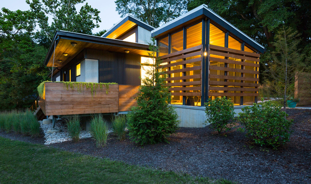 На фото: маленький, одноэтажный, черный дом в современном стиле с облицовкой из металла и односкатной крышей для на участке и в саду с