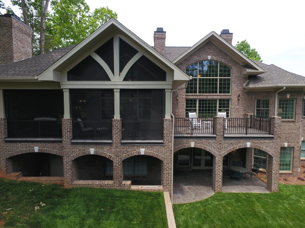 Example of a large classic brown two-story brick house exterior design in Charlotte with a hip roof and a shingle roof