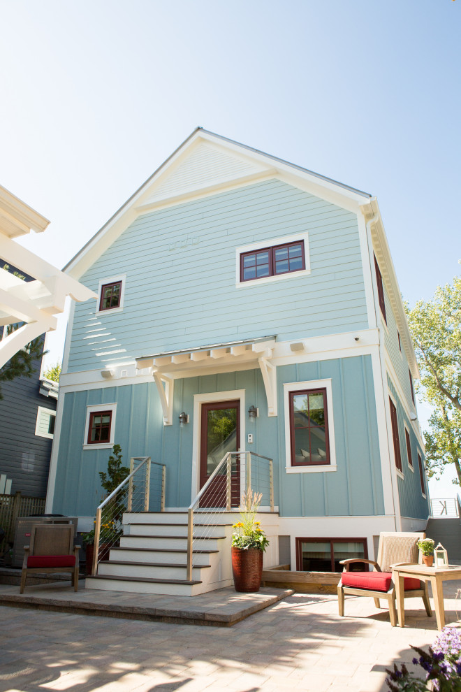 Esempio della villa blu stile marinaro a due piani di medie dimensioni con rivestimento con lastre in cemento, tetto a capanna e copertura in metallo o lamiera