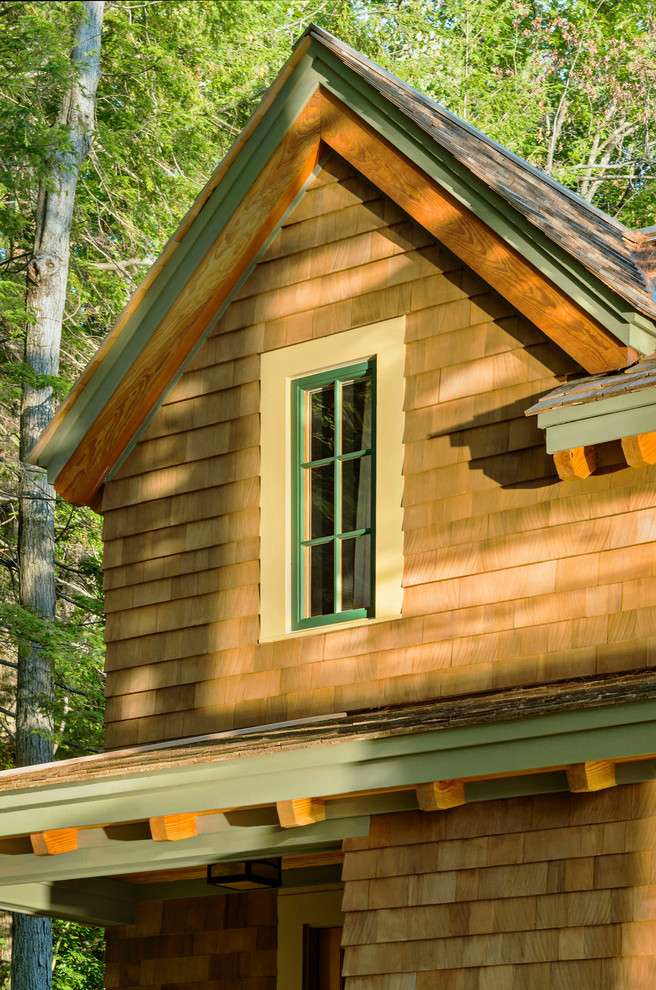 Cette image montre une petite façade de maison marron chalet en bois à un étage avec un toit à deux pans.