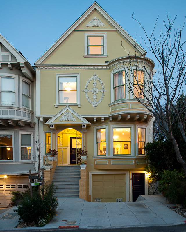 Mid-sized victorian yellow three-story stucco exterior home idea in San Francisco
