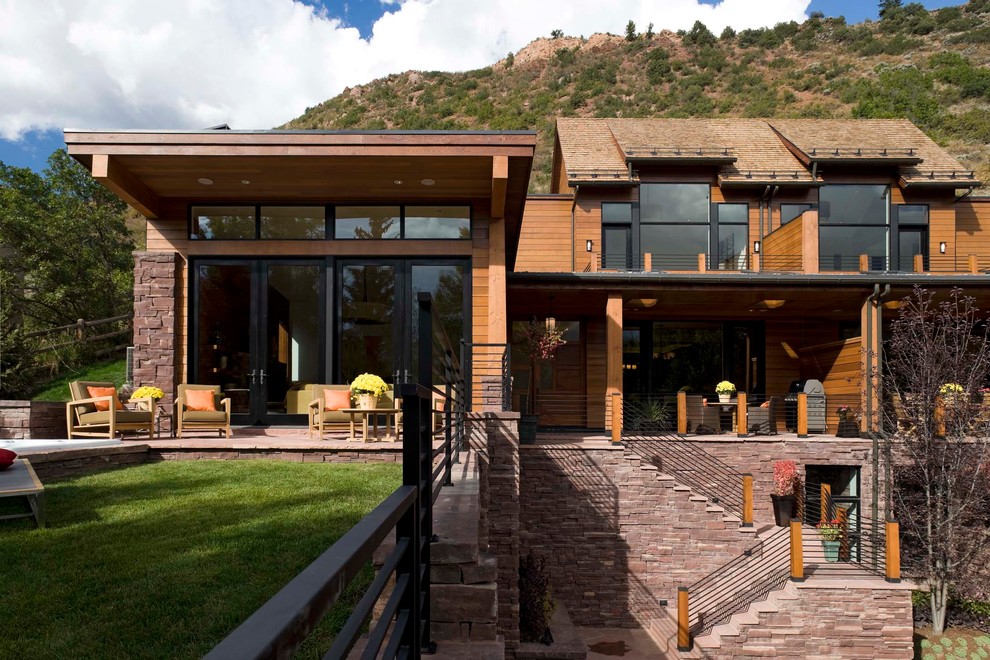 This is an example of a large contemporary house exterior in Denver with three floors and wood cladding.