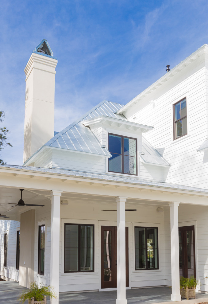 Esempio della facciata di una casa grande bianca country a due piani con rivestimento con lastre in cemento e tetto a capanna