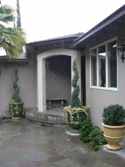 Modelo de fachada de casa gris clásica de tamaño medio de una planta con revestimiento de estuco, tejado a cuatro aguas y tejado de teja de madera