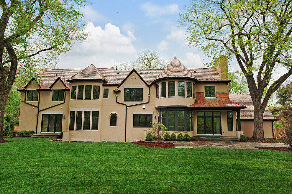 Cette image montre une grande façade de maison beige traditionnelle en stuc à un étage.