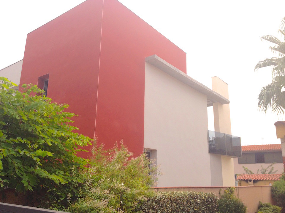 Идея дизайна: двухэтажный, красный дом среднего размера в стиле фьюжн с облицовкой из бетона и плоской крышей