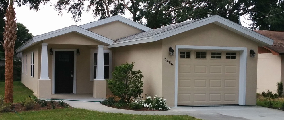 This is an example of a small and beige classic bungalow render house exterior in Tampa.