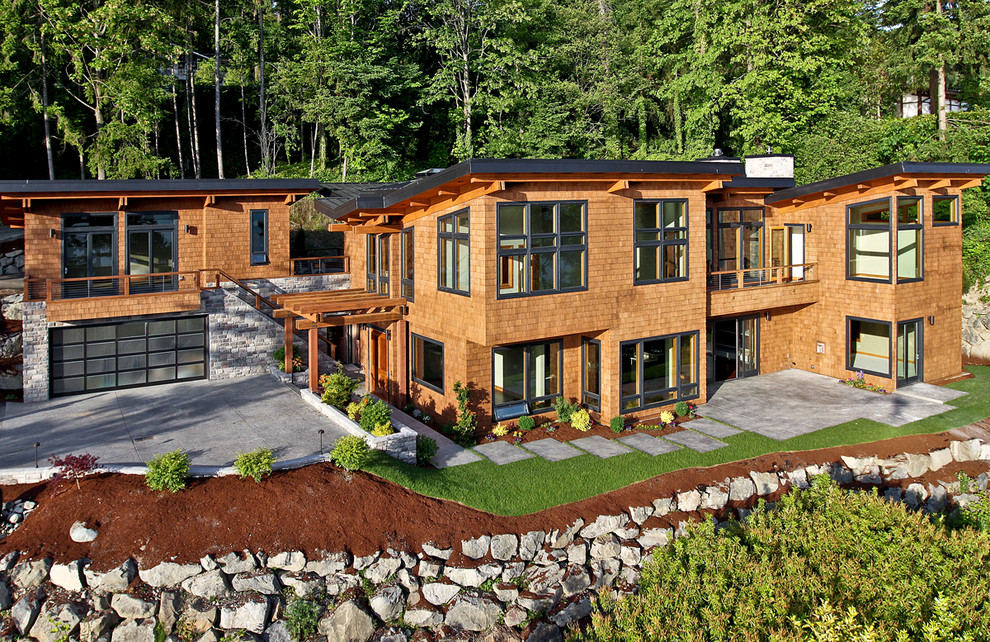 Immagine della facciata di una casa grande marrone contemporanea a due piani con rivestimento in legno e tetto piano