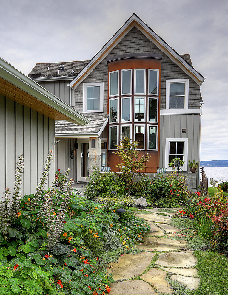 Ejemplo de fachada de casa gris costera de tamaño medio de dos plantas con tejado a dos aguas, revestimientos combinados y tejado de teja de madera