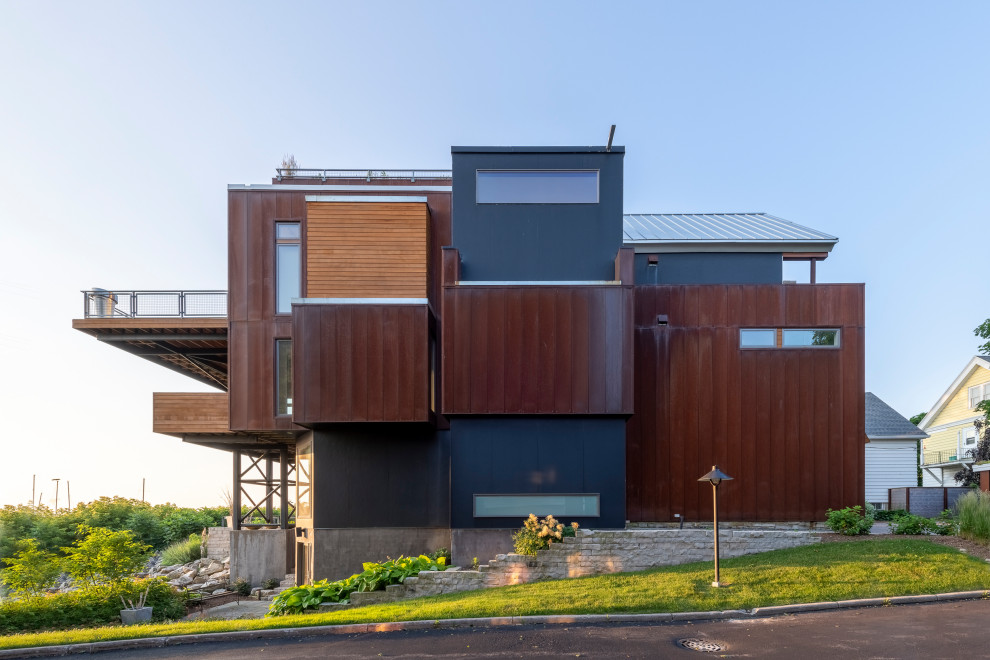Idée de décoration pour une façade de maison métallique et rouge urbaine à deux étages et plus avec un toit à deux pans, un toit en métal et un toit gris.