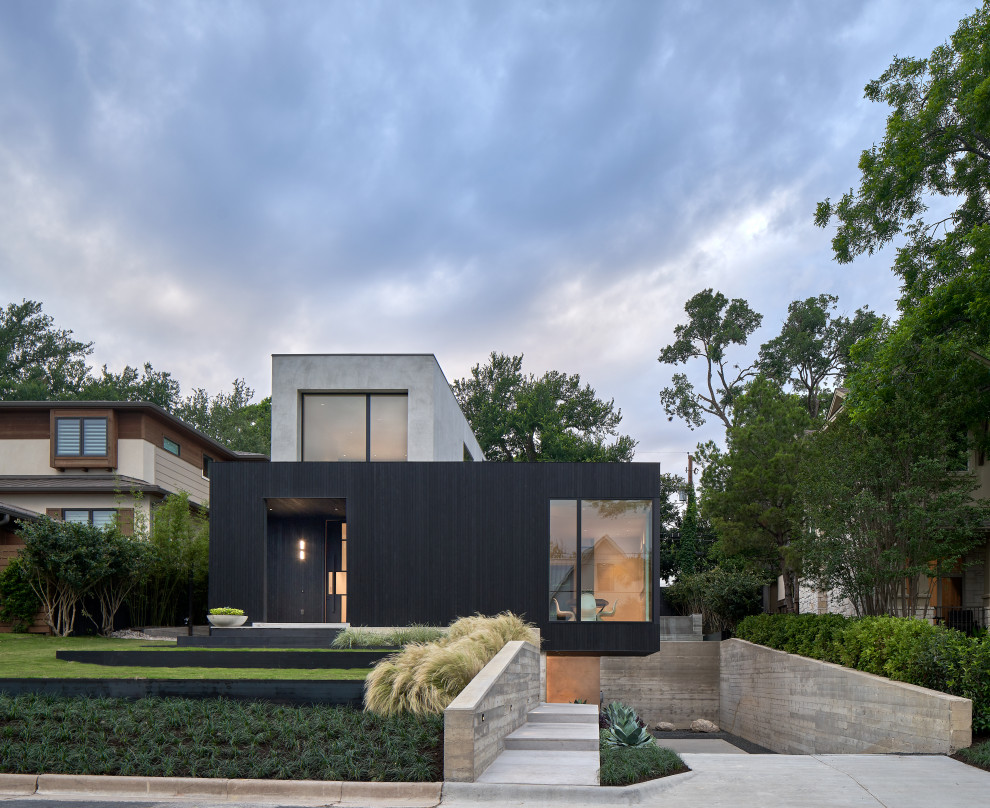 Imagen de fachada de casa negra minimalista de tres plantas con revestimiento de hormigón y tejado plano