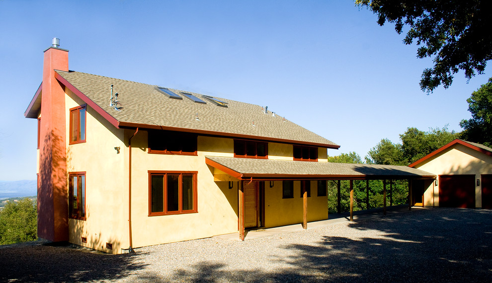 Esempio della facciata di una casa grande gialla contemporanea a due piani con tetto a padiglione e rivestimento in stucco
