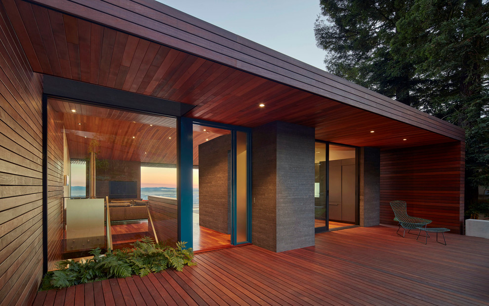 Cette photo montre une grande façade de maison marron moderne en bois à un étage avec un toit plat.