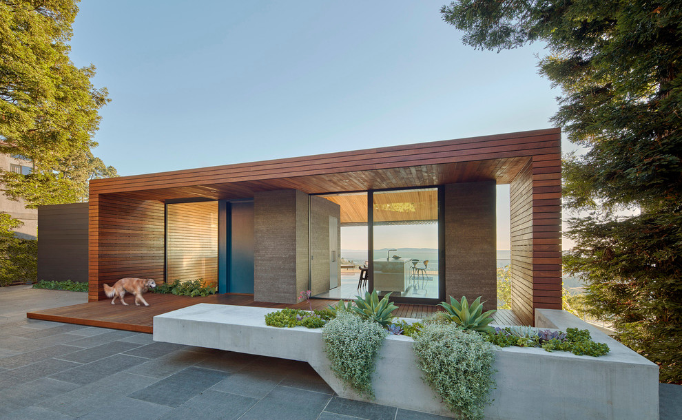 Design ideas for a brown and large modern bungalow house exterior in Orange County with wood cladding and a flat roof.