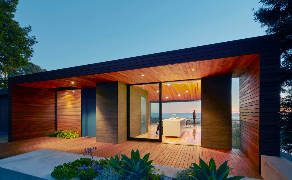 Cette image montre une grande façade de maison marron minimaliste en bois à un étage avec un toit plat.