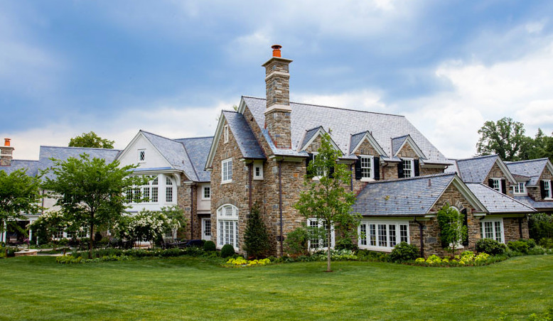 Aménagement d'une très grande façade de maison beige classique en pierre avec un toit à quatre pans.
