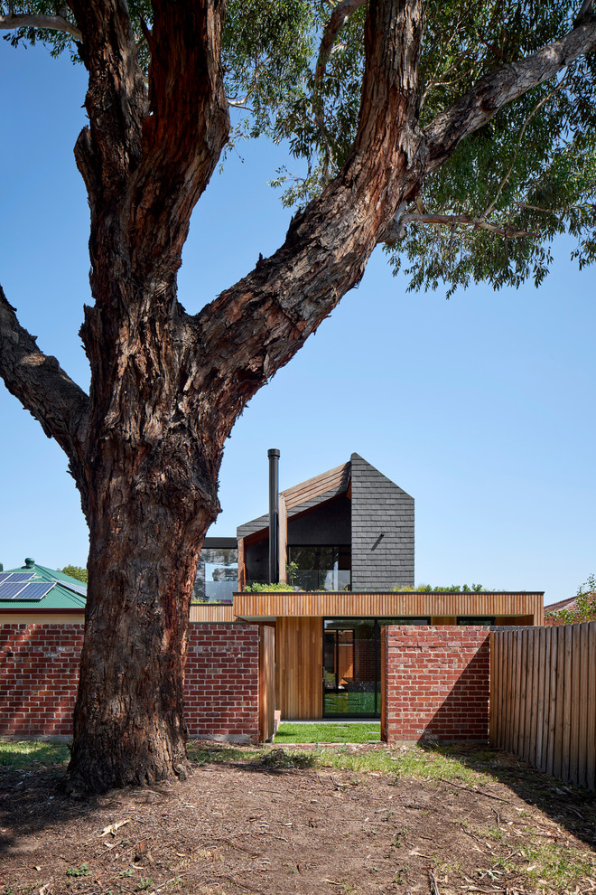 Réalisation d'une façade de maison noire design en bois avec un toit à deux pans et un toit en shingle.